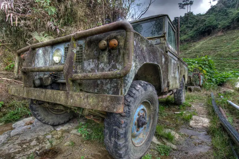 Old rusting Land Rover parked beside a tea slope